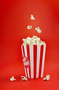 Falling Popcorn In A Striped Cardboard Box On A Red Background, Vertical View Stock Photography