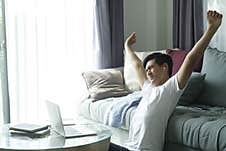 Young Businessman Sitting At Home Working At His Desk Hands Up And Stretching His Arms. Stock Image