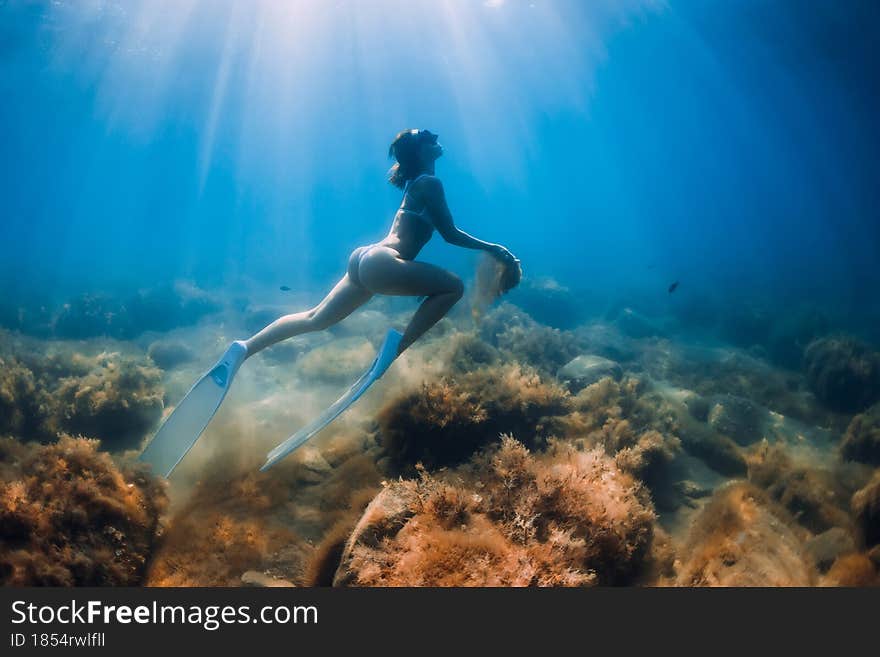 Free diver woman with sand in hands. Girl freediver with fins underwater in ocean