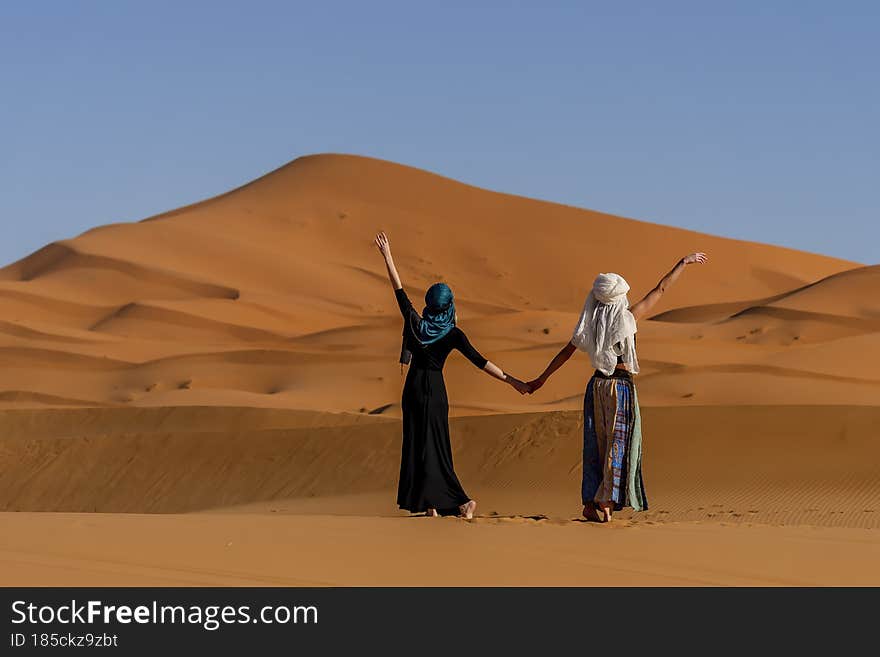 Two gorgeous models pose against the sand dunes in the great Sahara desert in Morocco. Two gorgeous models pose against the sand dunes in the great Sahara desert in Morocco
