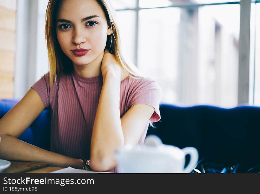 Portrait of attractive Caucasian female teenager with professional makeup looking at camera during free pastime in public cafeteria. Portrait of attractive Caucasian female teenager with professional makeup looking at camera during free pastime in public cafeteria