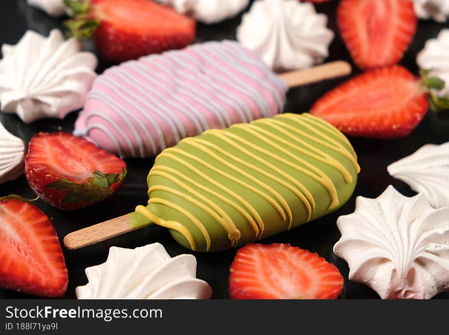 Two ice creams with meringue and strawberries on a black background, top view. Bright summer card with delicious food and berries