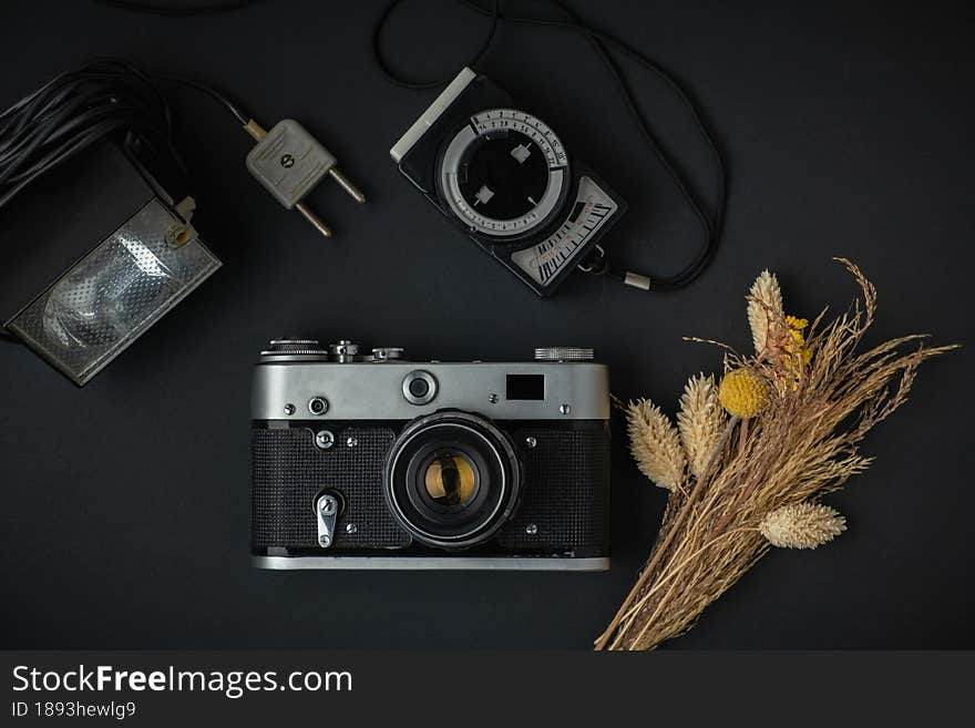 Retro camera on the black background. Old gear for photography. Stylish background for a photo enthusiast. Flat lay