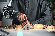 Man Hand Blocks Wood Block From Many Row Falling Wooden Block Like Domino To House Model Stock Photos