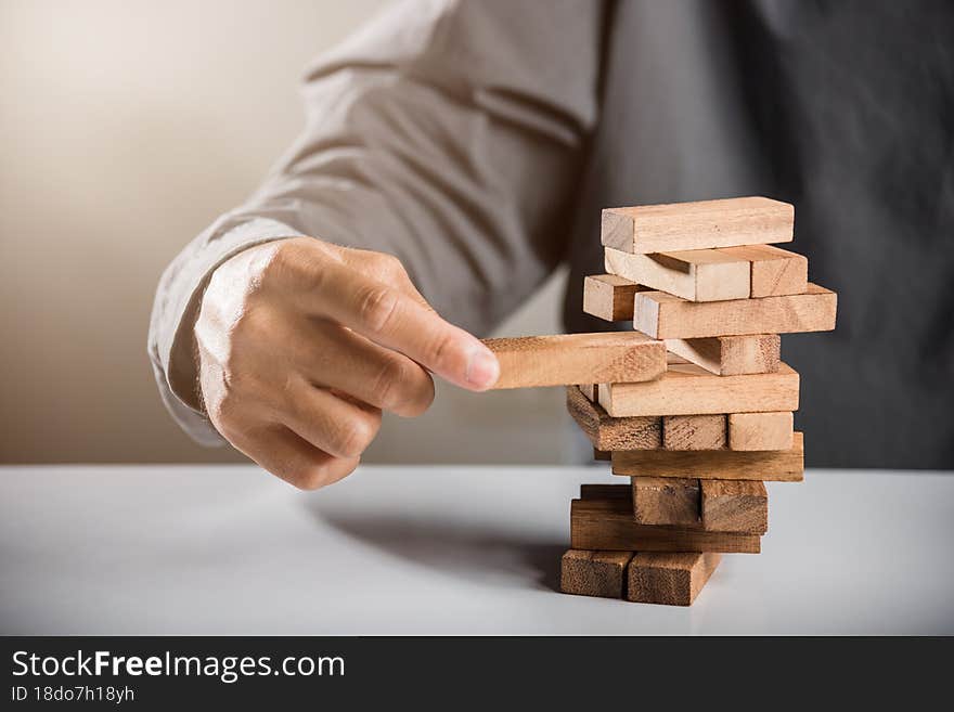 Alternative risk plan. Business hand playing tower wooden blocks game, man pull one wood block from tower he clenched his fist, show great joy in accomplishing it, Business gambling growth concept