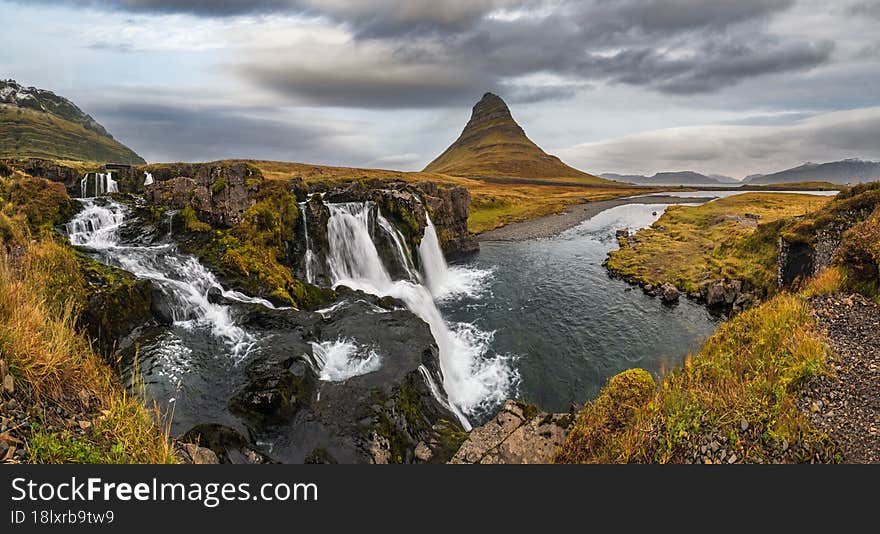 Famous picturesque Kirkjufell mountain and Kirkjufellsfoss waterfall next to Grundarfjordur at West Iceland autumn dusk view.