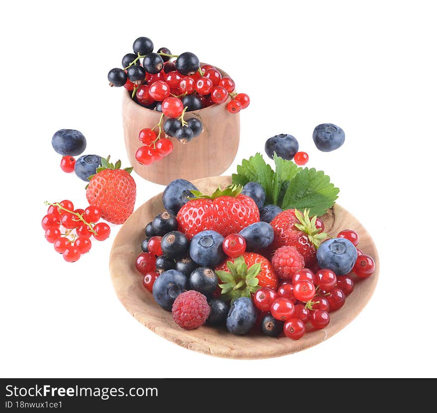 Assortment of fresh blueberries, raspberries, strawberries and black currants, in a wooden bowl, on an isolated white background