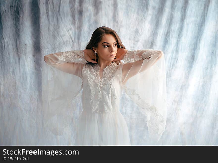 Close up portrait of young gorgeous bride looking away at studio while posing over blue background. Concept of bridal photo session and art. Stock photo