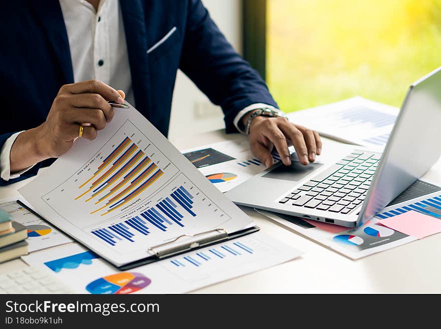 Businessman holding documents containing financial statistics, stock photos, discussion and data analysis, charts and graphs, charts, diagrams, business, and work concepts...