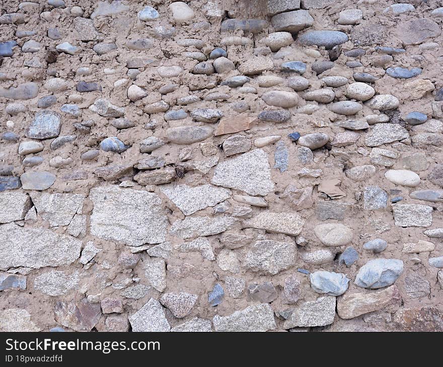 Background Image Of Wall Texture Made Of Rocks And Pebbles Made Of Mud.