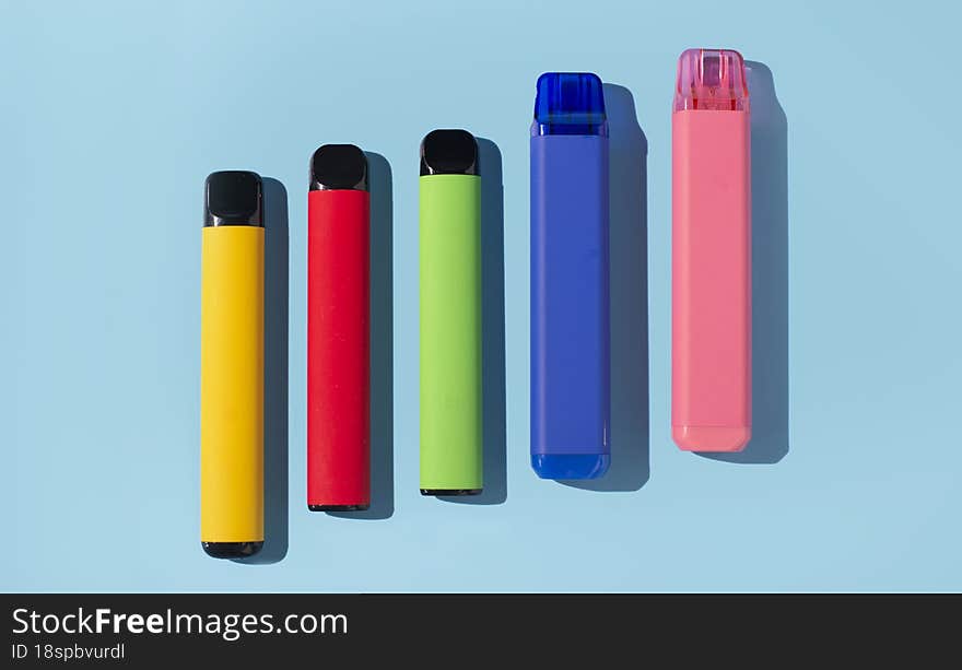 Set of colorful disposable electronic cigarettes on a blue background. The concept of modern smoking. Top view