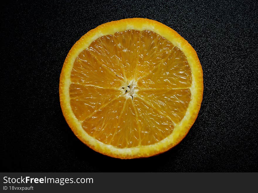 A piece of orange on a black background.