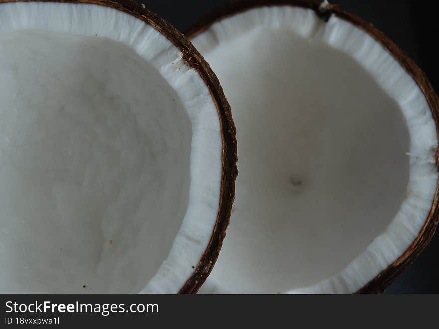 Two Halves Of Coconut On A Black Background.