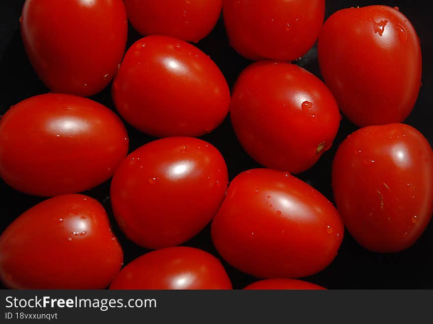 Group Of Red Tomatoes On Black Background.