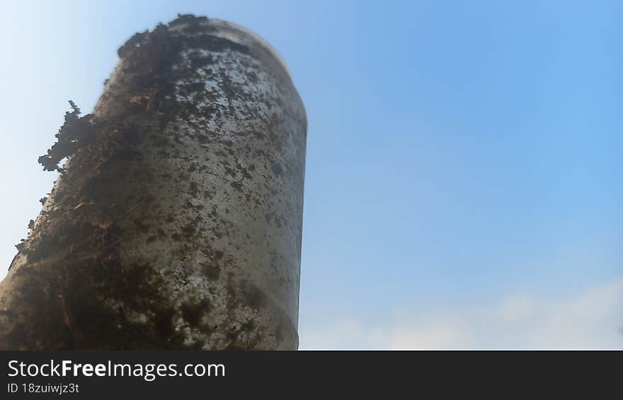 A Bottle Made Of Glass, Looks Very Dirty, Soaring Into The Blue Sky With White Clouds.