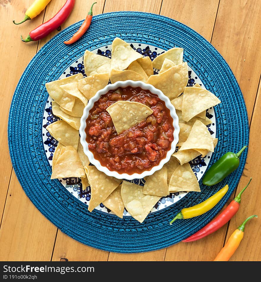 Top down view of authentic tortilla chips and fresh gourmet salsa with chilli peppers.