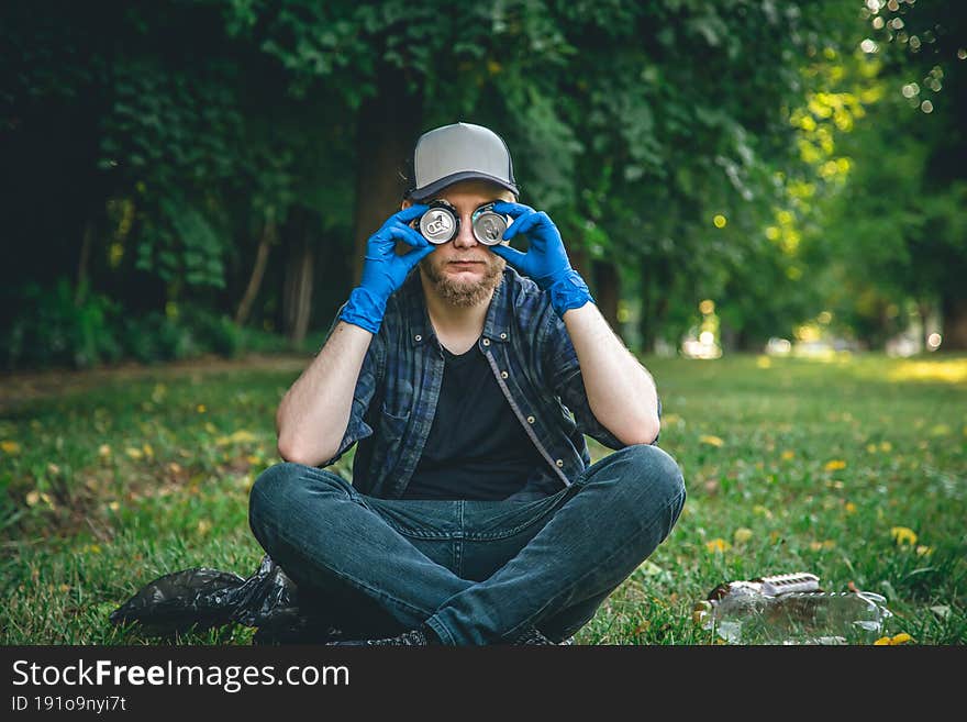 A young man in the forest cleaning, portrait with tin cans, the concept of love for nature and care for the environment. A young man in the forest cleaning, portrait with tin cans, the concept of love for nature and care for the environment.