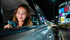 Asian Businesswoman Commuting From Office In Taxi Backseat With Mobile Phone On Road Stock Photography