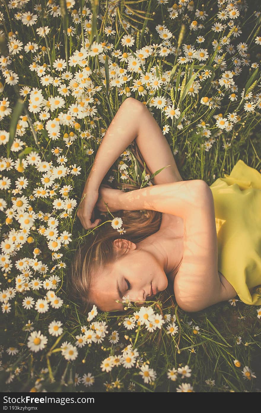 Portrait of young  woman with radiant clean skin lying down amid flowers on a lovely meadow on a spring/summer day