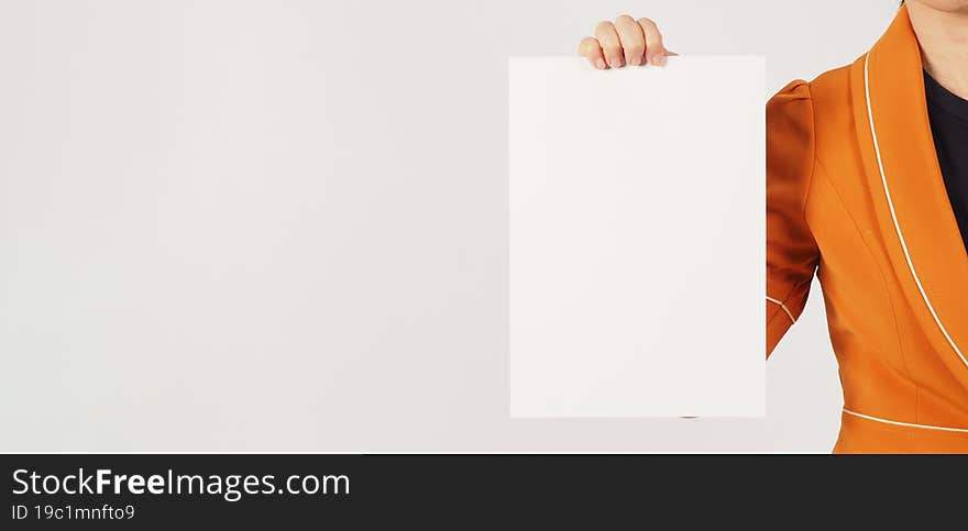 Woman is wearing a yellow mustard suit and holding the blank paper board on white background. Body part.