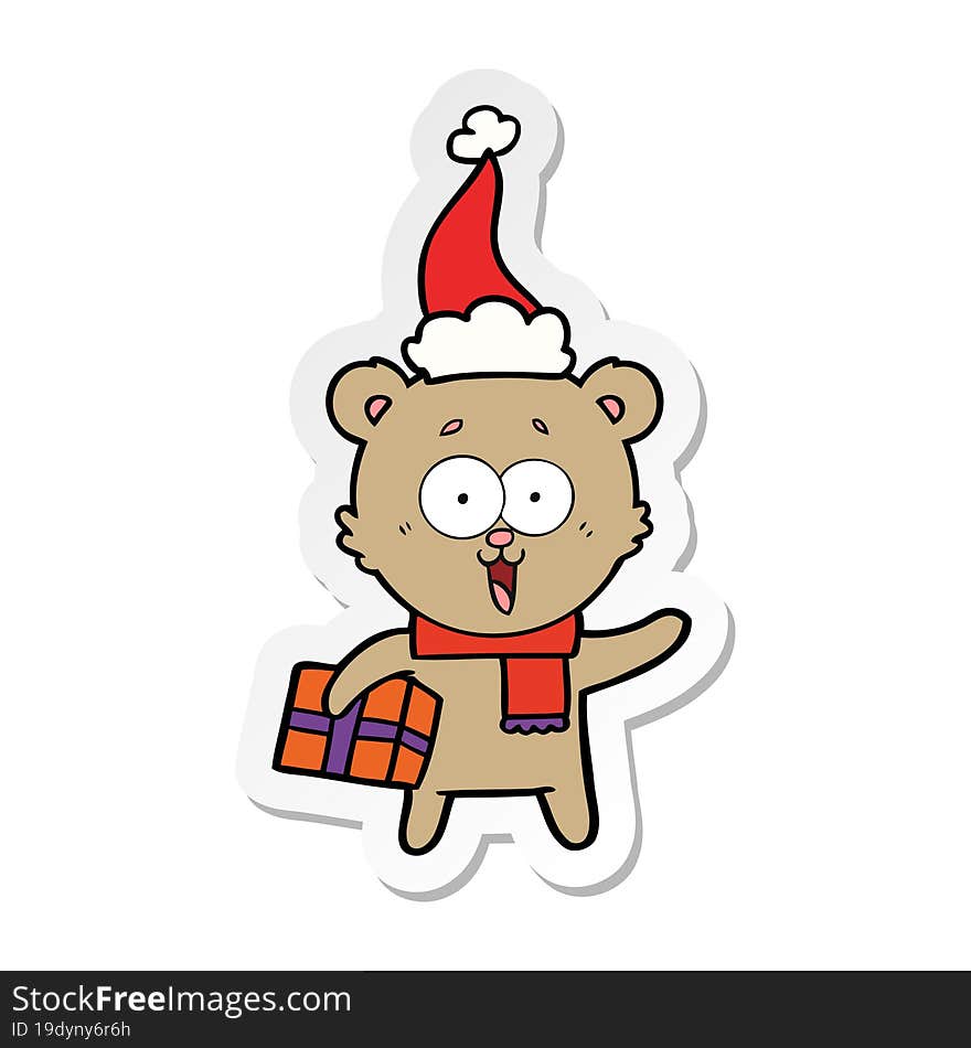 laughing teddy  bear with christmas present wearing santa hat