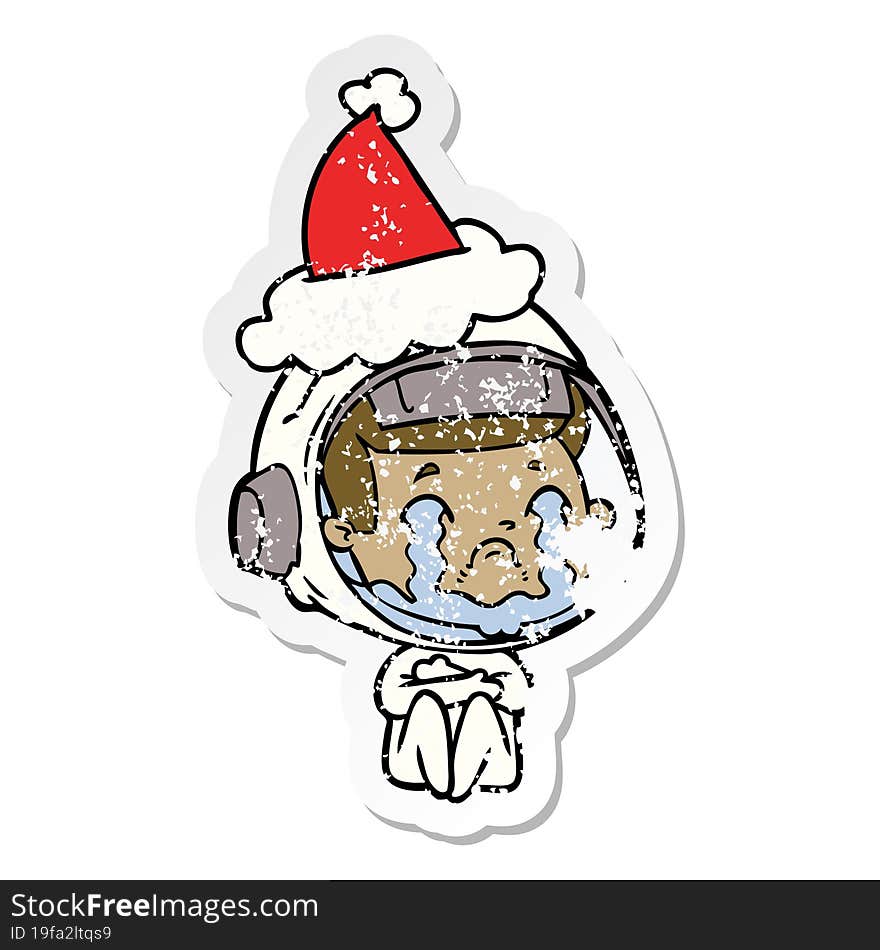 hand drawn distressed sticker cartoon of a crying astronaut wearing santa hat