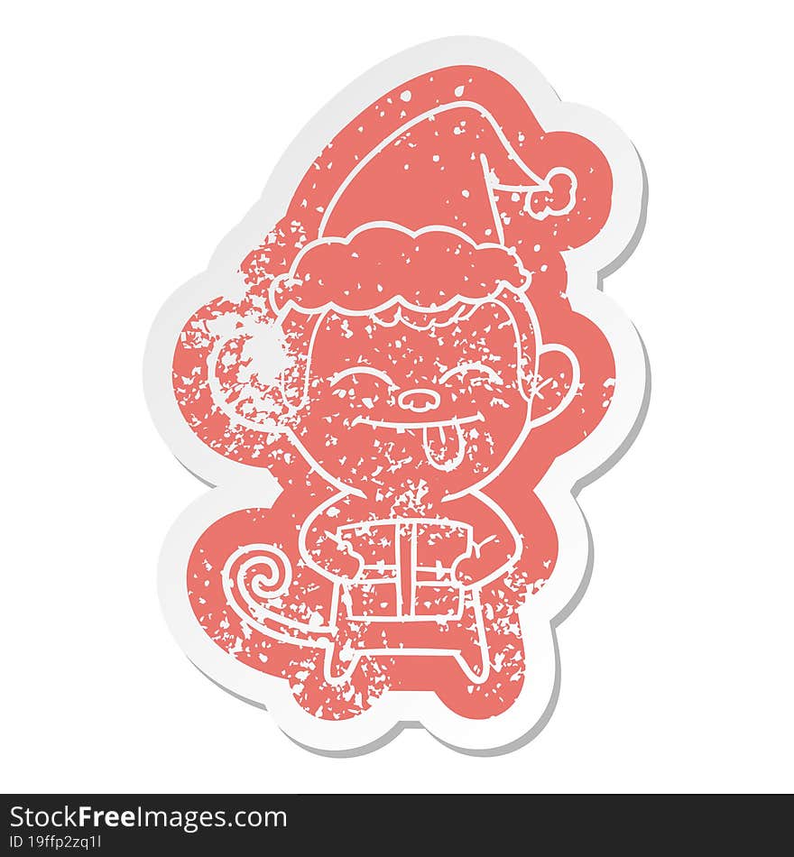 funny quirky cartoon distressed sticker of a monkey with christmas present wearing santa hat