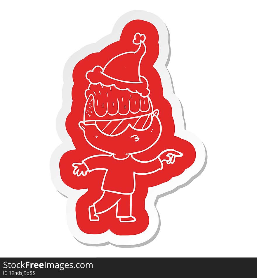 quirky cartoon  sticker of a boy wearing sunglasses pointing wearing santa hat