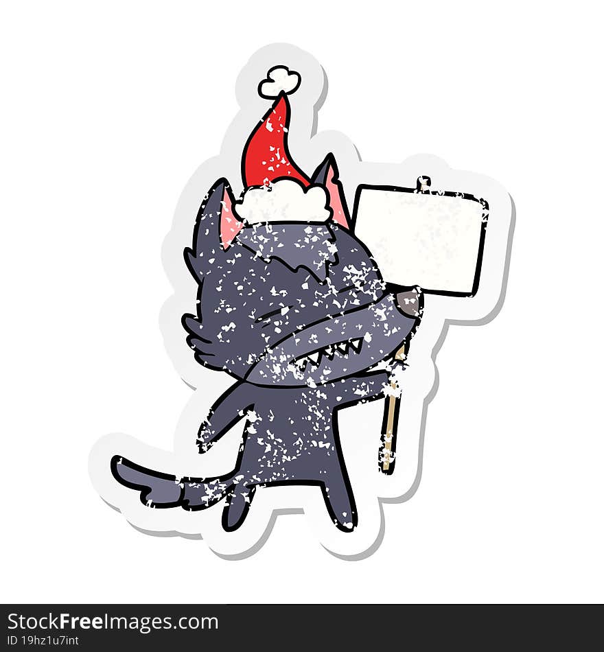 distressed sticker cartoon of a wolf with sign post showing teeth wearing santa hat