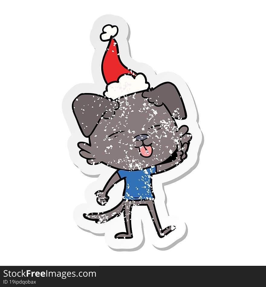 distressed sticker cartoon of a dog sticking out tongue wearing santa hat