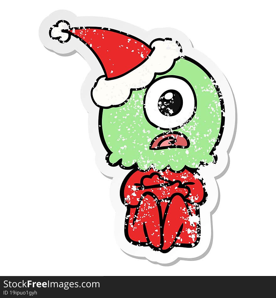 hand drawn distressed sticker cartoon of a cyclops alien spaceman wearing santa hat