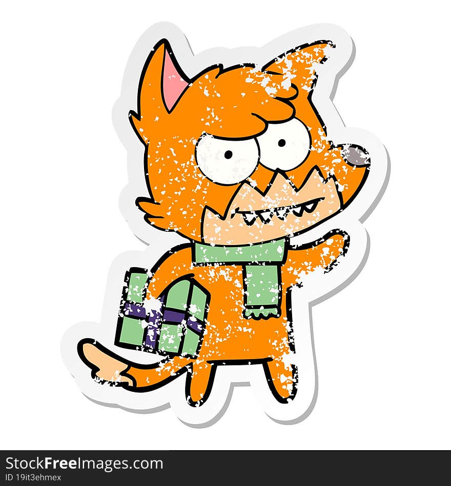 distressed sticker of a cartoon grinning fox with christmas present