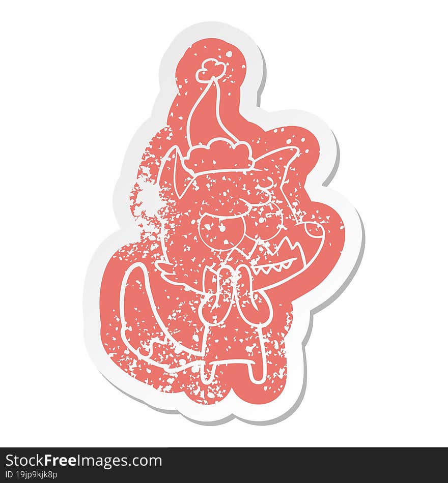 cartoon distressed sticker of a grinning fox wearing santa hat