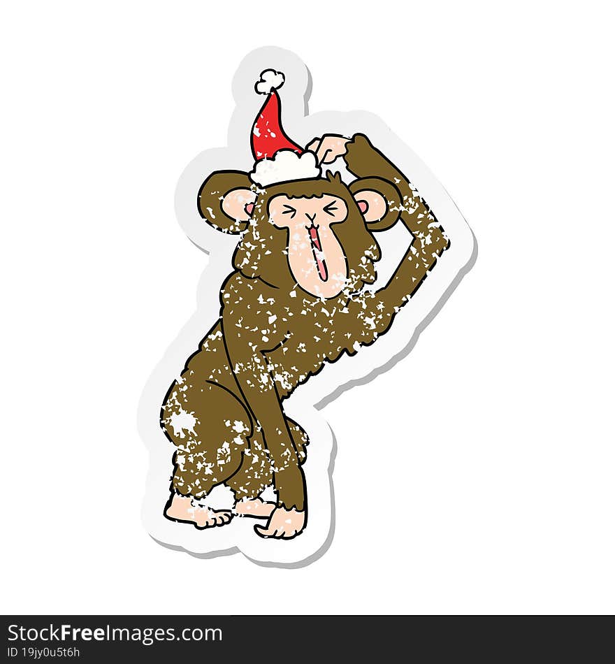 hand drawn distressed sticker cartoon of a chimp scratching head wearing santa hat