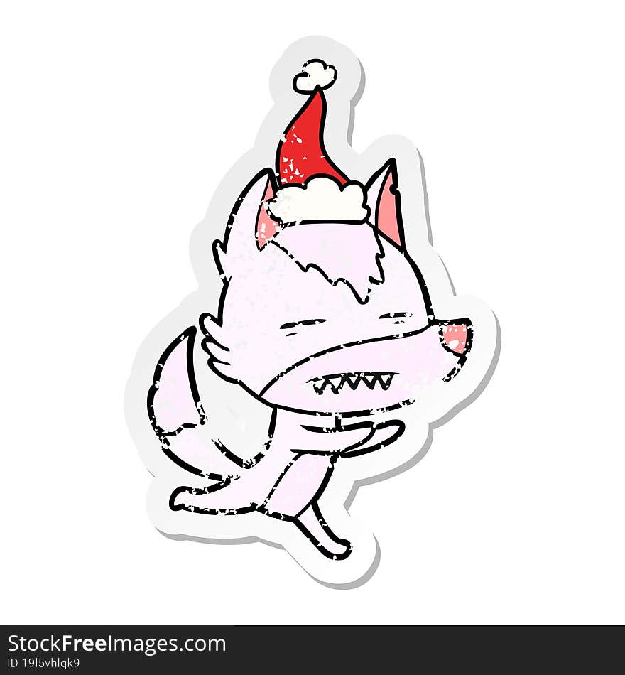 distressed sticker cartoon of a wolf showing teeth wearing santa hat