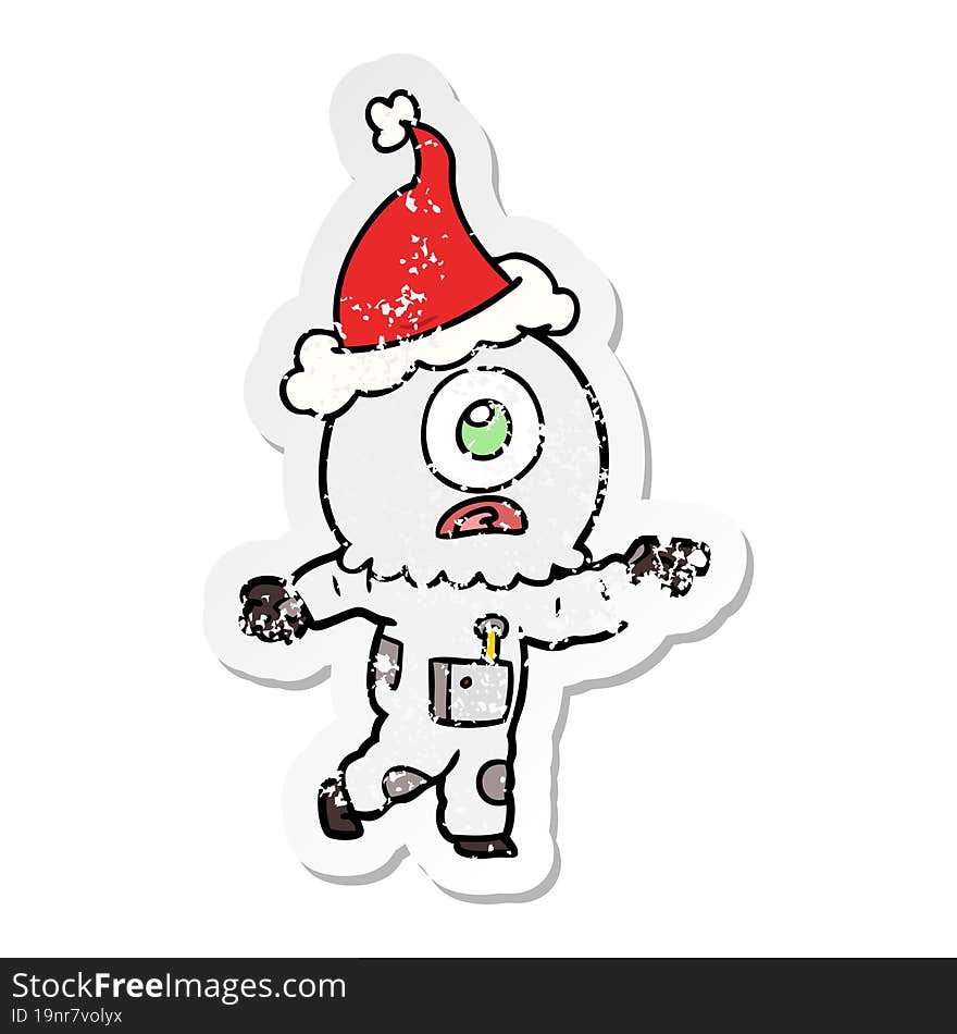 hand drawn distressed sticker cartoon of a cyclops alien spaceman pointing wearing santa hat