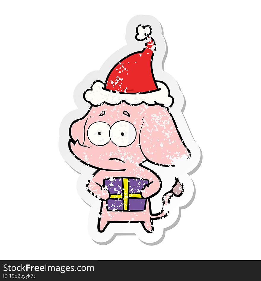 hand drawn distressed sticker cartoon of a unsure elephant with christmas present wearing santa hat