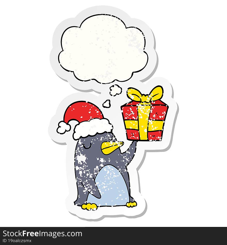 cartoon penguin with christmas present and thought bubble as a distressed worn sticker