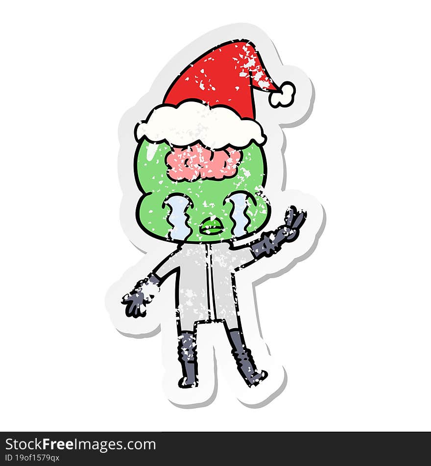 Distressed Sticker Cartoon Of A Big Brain Alien Crying And Giving Peace Sign Wearing Santa Hat