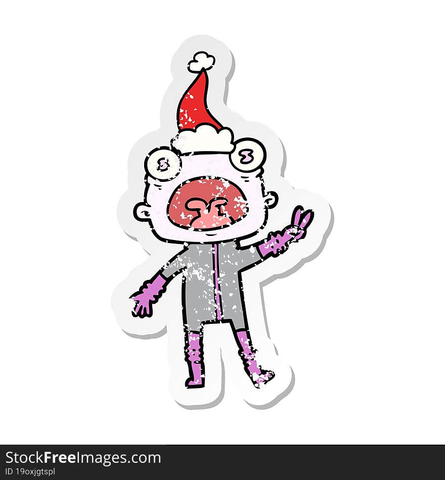 hand drawn distressed sticker cartoon of a weird alien waving wearing santa hat