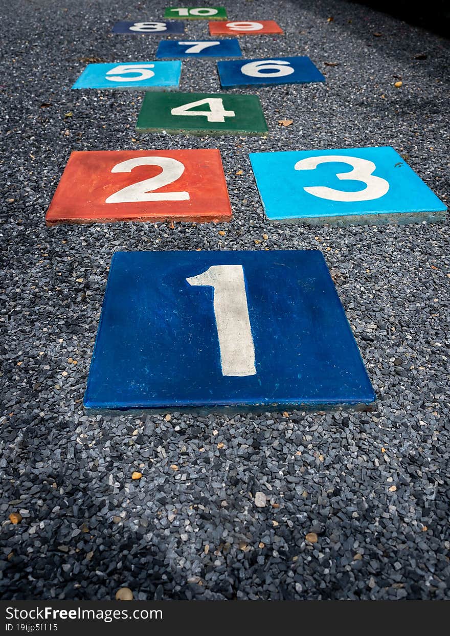 Number 1 on multicolored hopscotch on the asphalt ground in the kids playground with nobody, outdoors game activities for children, vertical style. Growth and education concept. Number 1 on multicolored hopscotch on the asphalt ground in the kids playground with nobody, outdoors game activities for children, vertical style. Growth and education concept.