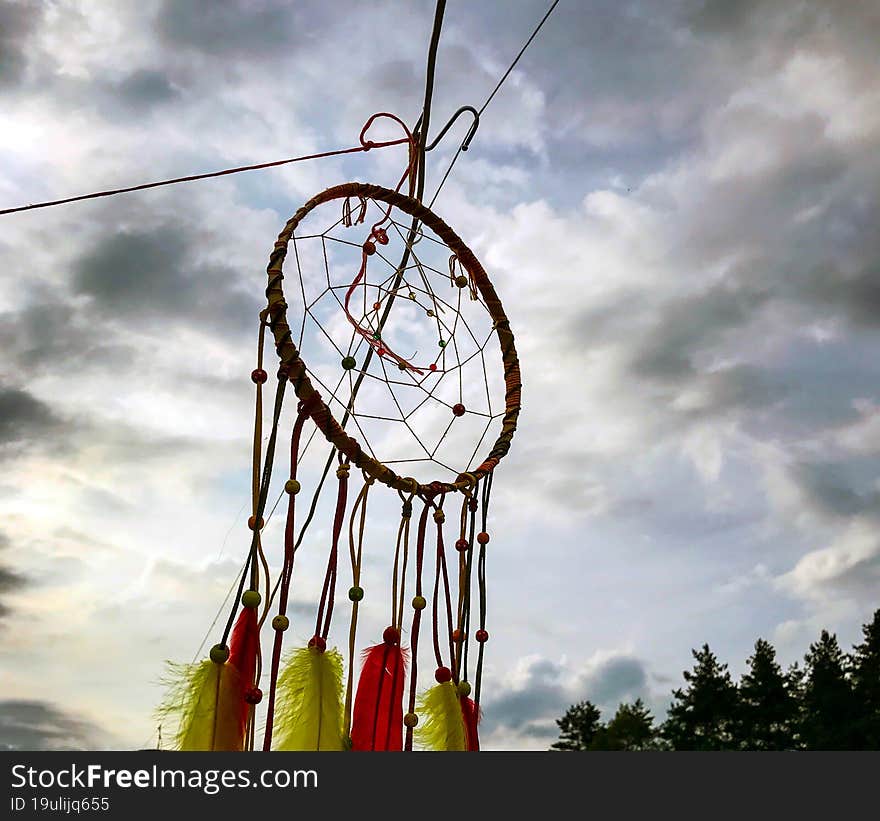 Dream Catcher. Photo of a dream catcher against the background of the sky and the forest.