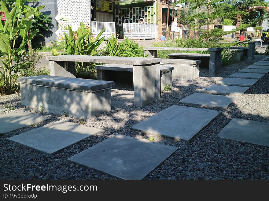 a photo of a table and chairs made of cement on the side of the road