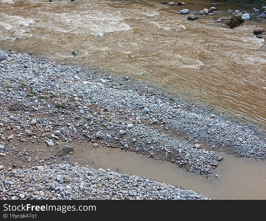 a muddy stream gushing past a rocky terrain