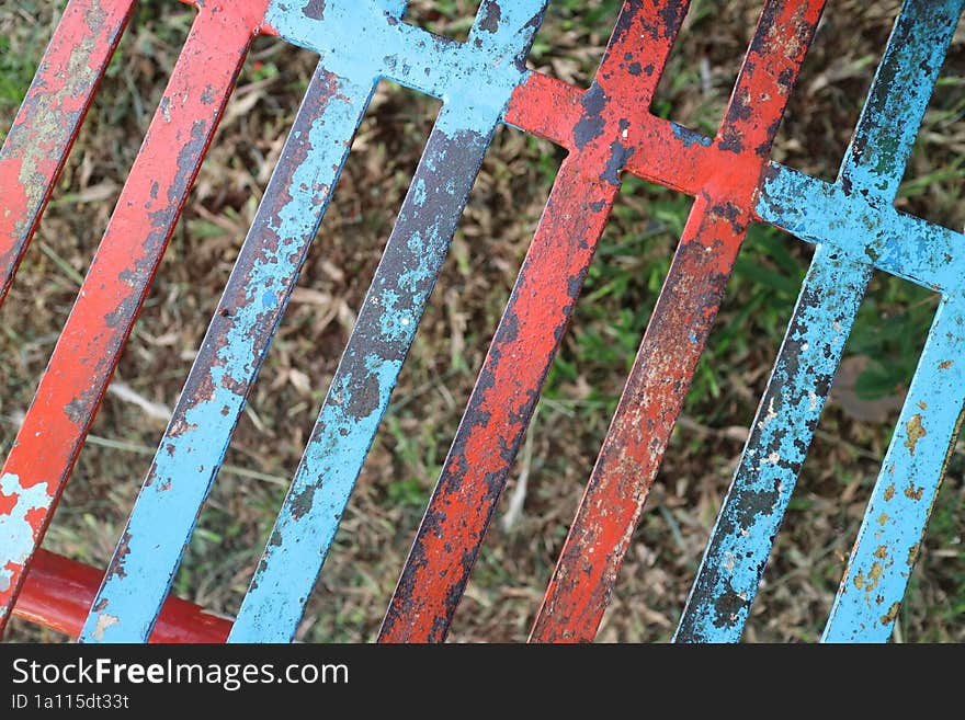 a photo of a iron trellis with red and blue paint that has peeled off