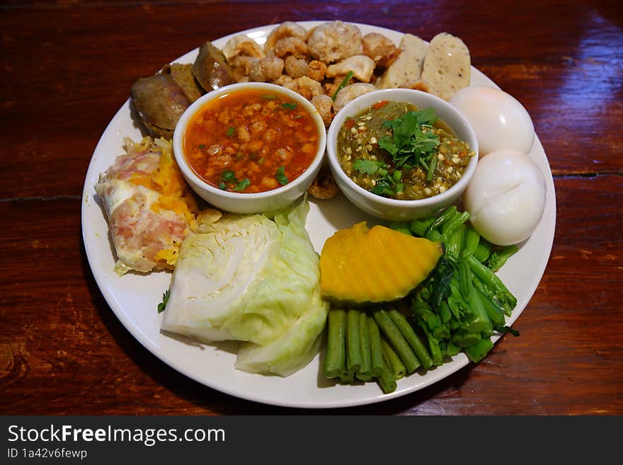 A top view shot of nam prik & x28 chili& x29  served with sai oua & x28 Thai sausage& x29 , kab moo & x28 crispy pork rind& x29 , eggs, and boiled vegetables