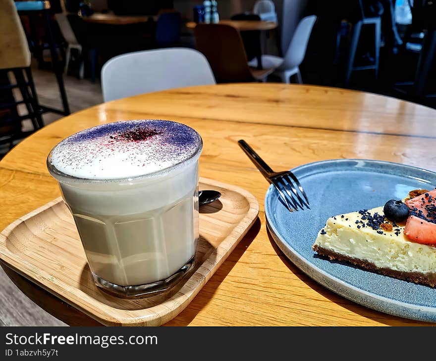 Cup of raff coffee on a tray with cheesecake on the table