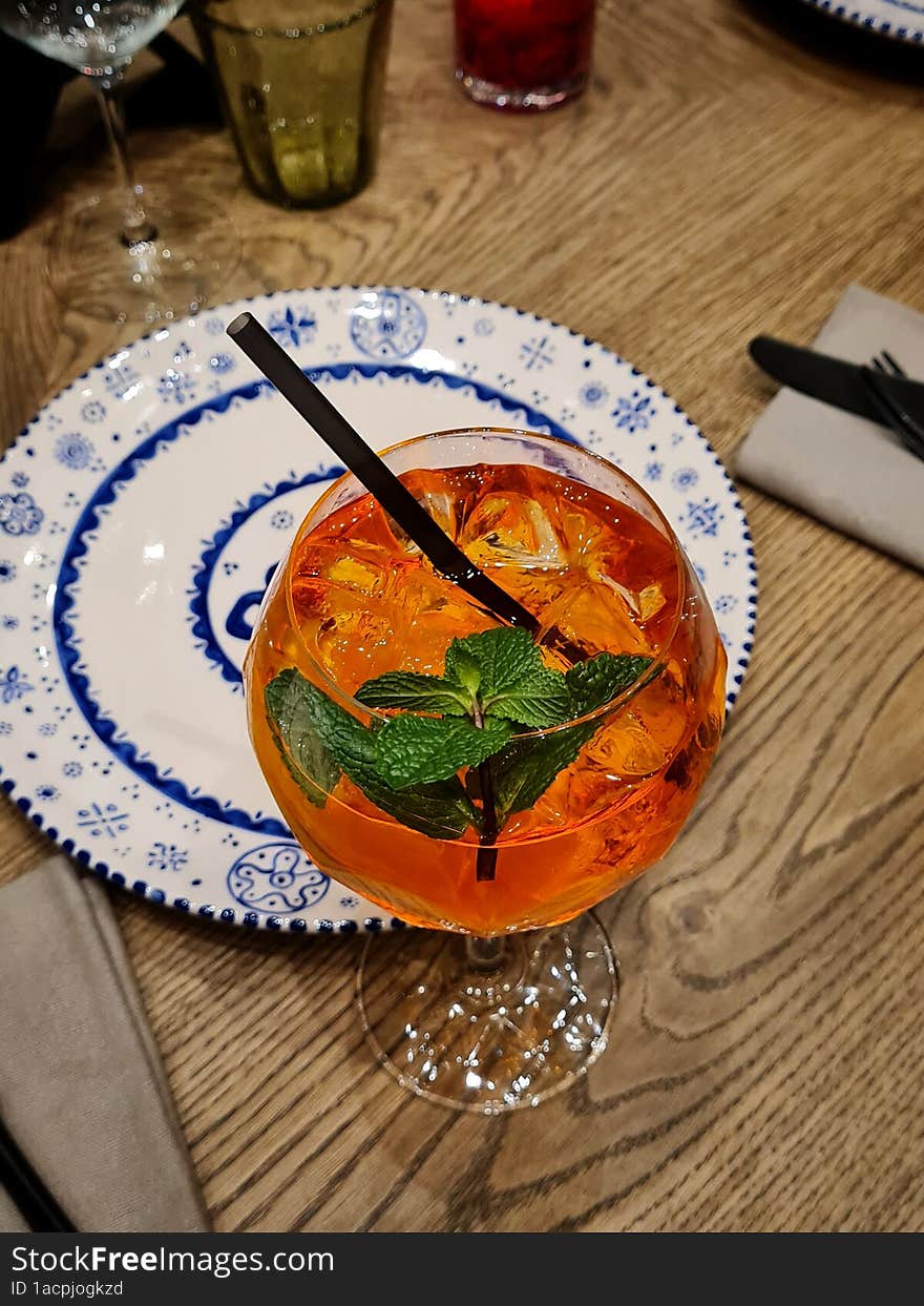 Aperol cocktail on a table with a black straw