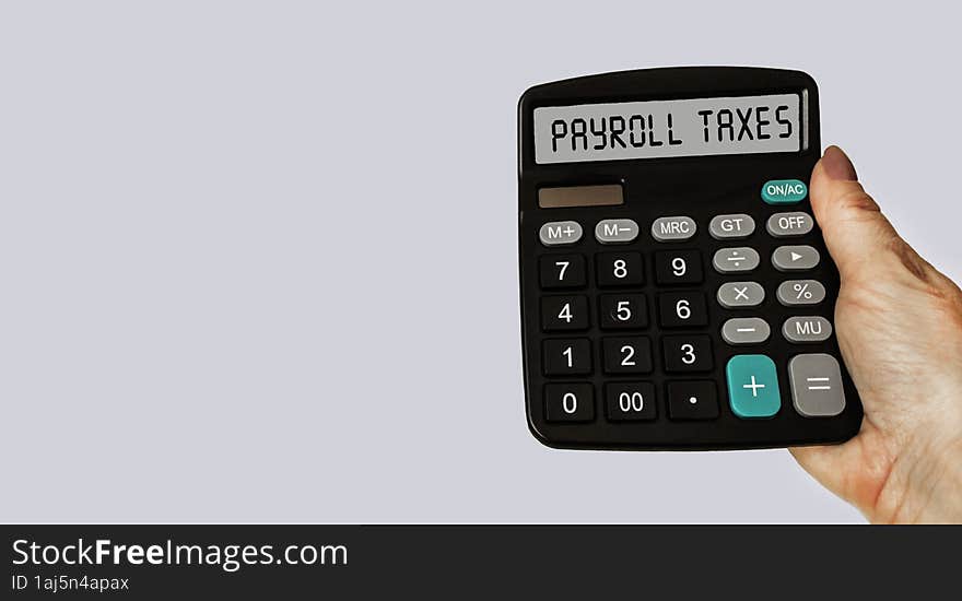 Payroll taxes concept on calculator display. A woman& x27 s hand is holding a calculator. The concept of taxes on business and wa