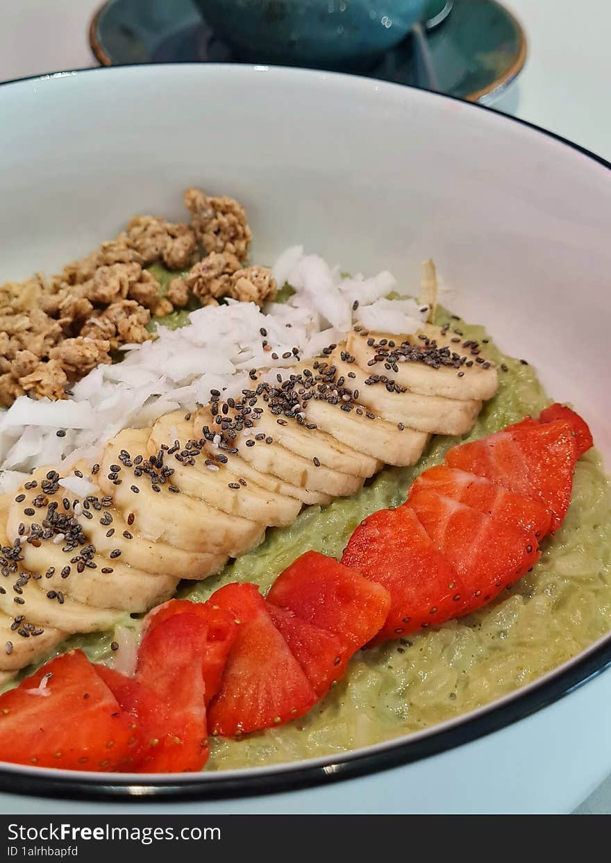 Bright green porridge with pieces of fruit: strawberry and banana